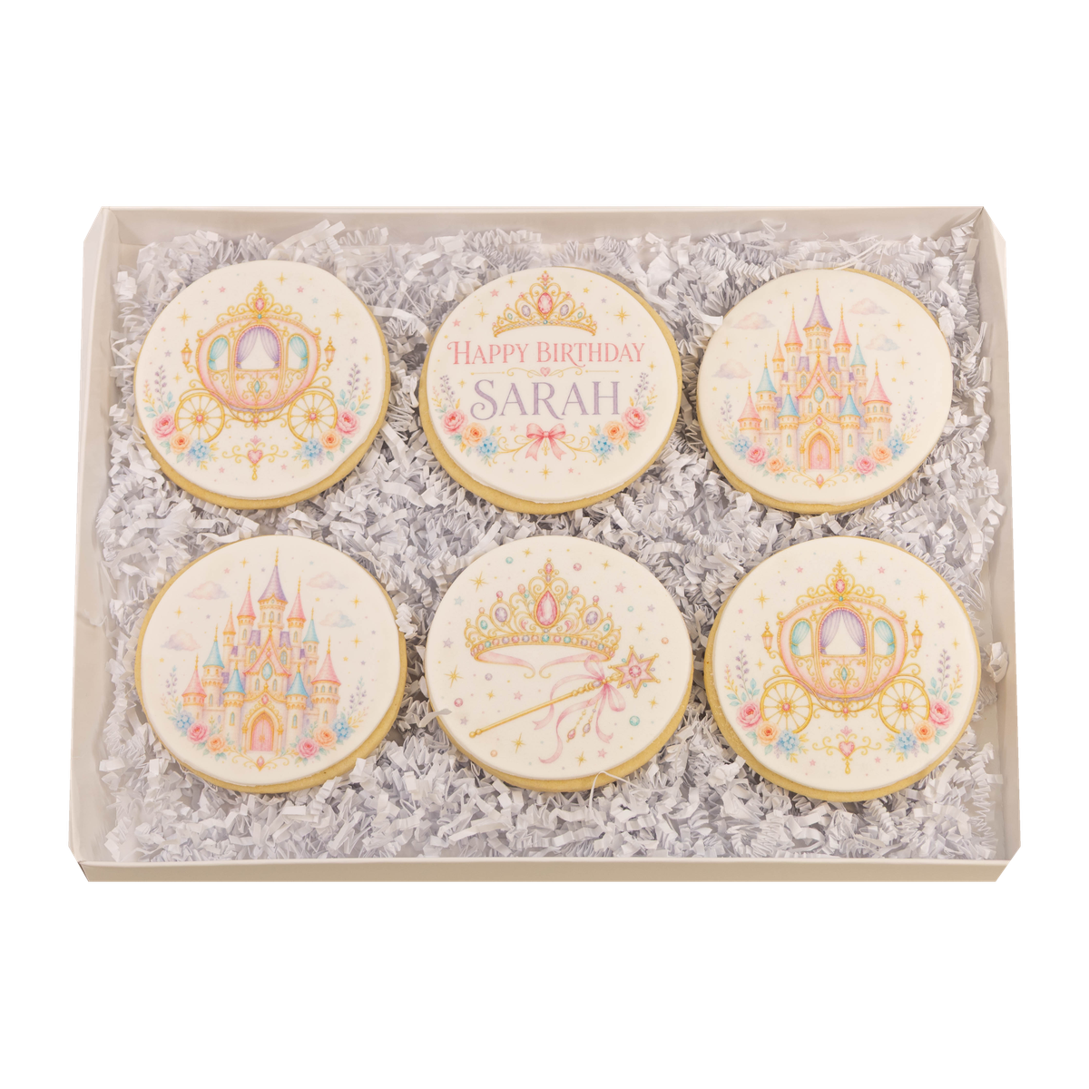 Open personalized princess birthday cookie gift box with six pink and gold sugar cookies featuring a dress, castle, carriage, crowns, and name